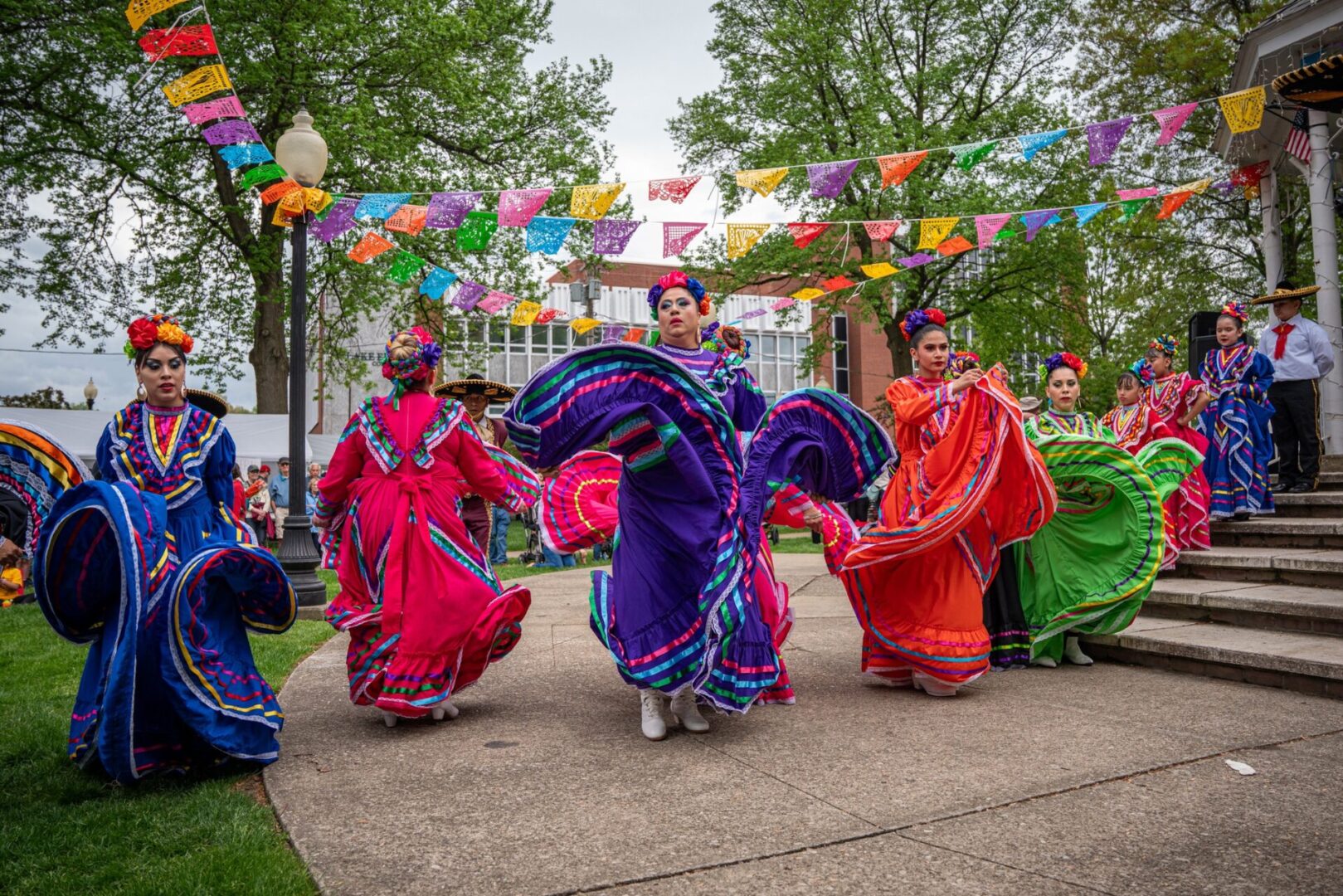 Colorful traditional dancers perform outdoors under festive decorations.