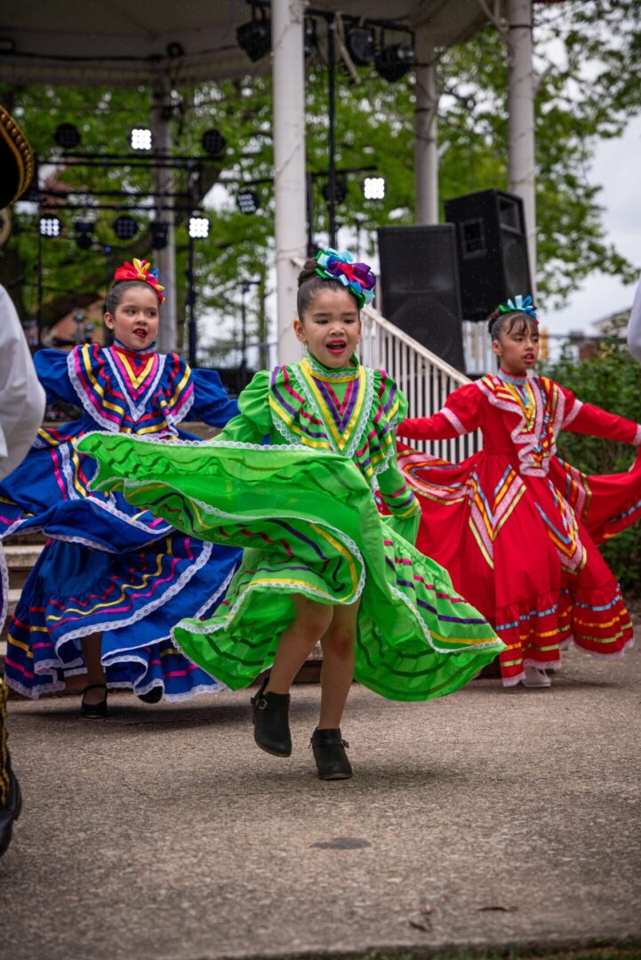 Young dancers in colorful traditional dresses performing outdoors.